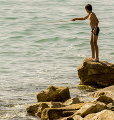 Niño pescando en la costa