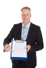 Confident Businessman Offering Pen To Sign Contract Paper