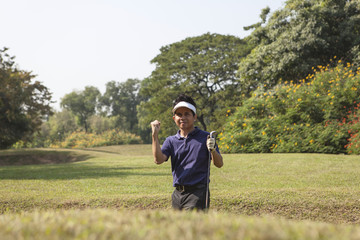 Young male golf player grey pants chipping golf ball out of a sa