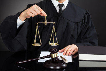 Judge Holding Weight Scale At Desk