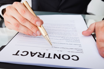 Businessman Signing Contract Paper At Desk