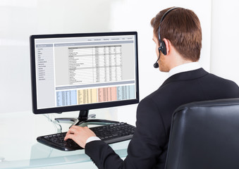 Businessman In Headset Using Computer At Desk
