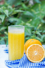Glass of freshly pressed orange juice with sliced orange  on woo