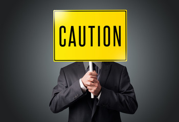 Businessman holding a caution sign