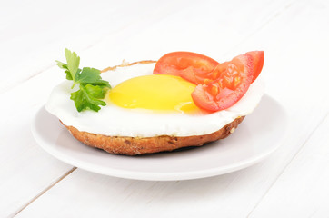 Sandwich with fried egg, tomato slices and parsley