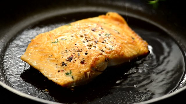 Fresh salmon steak cooking in a frying pan close up