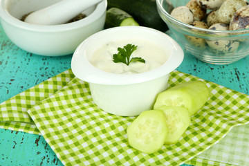 Cucumber yogurt in bowl, on color napkin, on wooden background