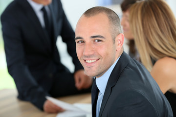 Smiling young businessman with dark suit in meeting