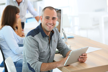 Young smiling man in training class using digital tablet
