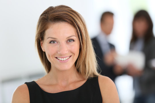 Portrait of attractive businesswoman, people in background