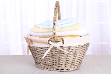 Colorful towels in basket on light background