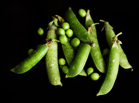 Fresh green peas isolated on black background