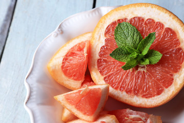 Ripe grapefruits on plate on color wooden background