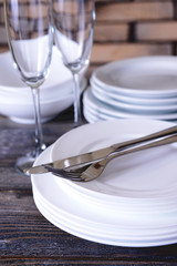 Set of white dishes on table on brick-wall background