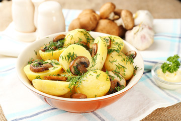 Young boiled potatoes with mushrooms on table, close up