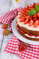 Delicious biscuit cake with strawberries on table close-up