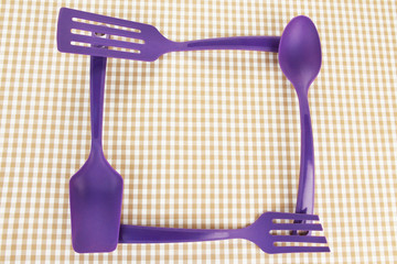Plastic kitchen utensils on fabric background