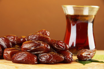 Dried dates with cup of tea on table on brown background