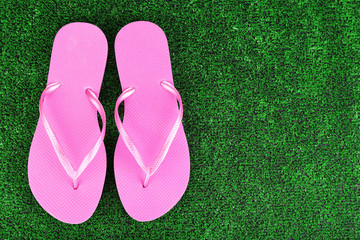 Bright flip-flops on green grass background