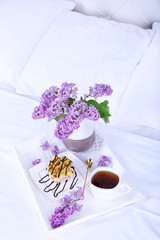 Wooden tray with light breakfast on bed