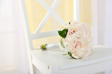 Beautiful wedding bouquet on chair on light background