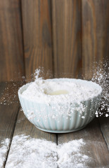 Flour in bowl on table on wooden background