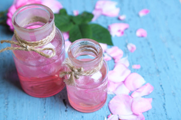 Rose oil in bottles on color wooden background
