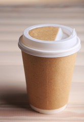 Paper cup of coffee on wooden table