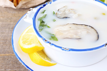 Tasty soup with oysters on wooden table