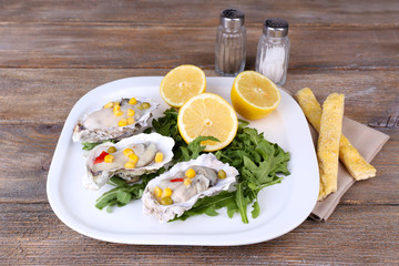 Tasty cooked oysters in shell on wooden table