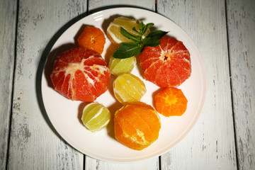 Citrus fruits without skin, on plate, on wooden background