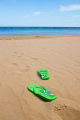 Fototapeta na wymiar green sandals on sandy beach