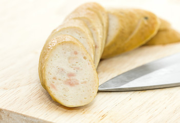 Sausage with knife over cutting board