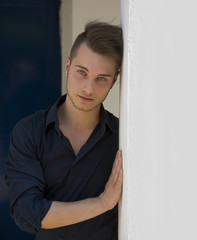 Attractive young blond man leaning against wall