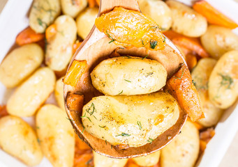 Roasted potatoes with carrot on the wooden ladle