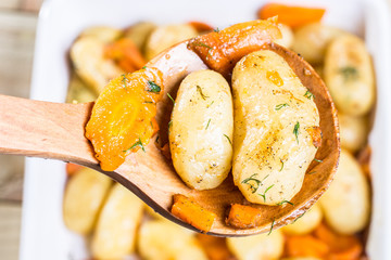 Roasted potatoes with carrot on the wooden ladle