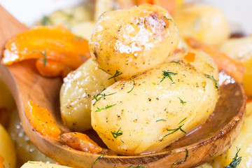 Roasted potatoes with carrot on the wooden ladle