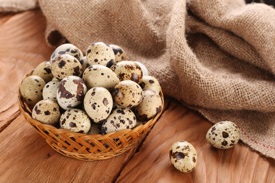 quail eggs in a wicker basket on the background of wooden planks