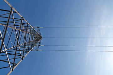 Transmission power lines tower over clear blue sky