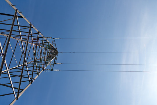 Transmission power lines tower over clear blue sky