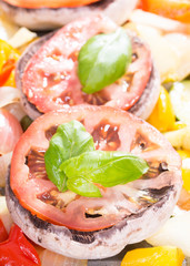 Raw mushrooms with cooked vegetables and leafs of basil