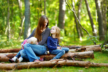 Naklejka na ściany i meble Two sisters and their mother sitting on a log