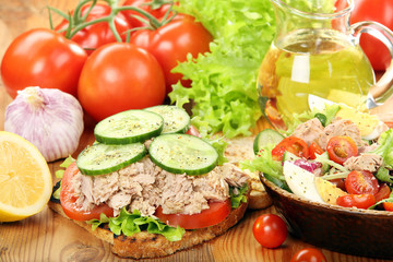 Sandwich with tuna and salad on wood background