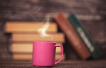 Books and cup of coffee on wooden background.