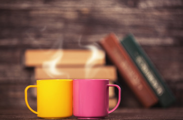 Two cups and books on background.