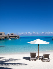 Umbrella and chaise lounges on a beach.