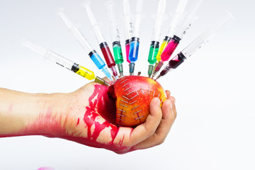 hand holding gmo apple surrounded by syringe with blood - obrazy, fototapety, plakaty