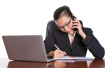 Asian businesswoman at her desk talking to a smart phone