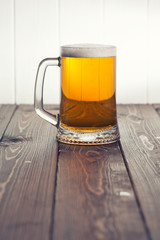 Mug of beer on wooden background