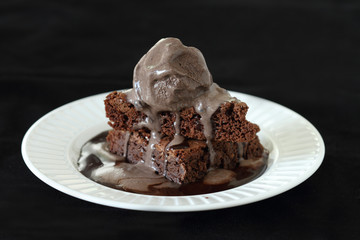 Slices of brownie covered with chocolate and chocolate ice cream